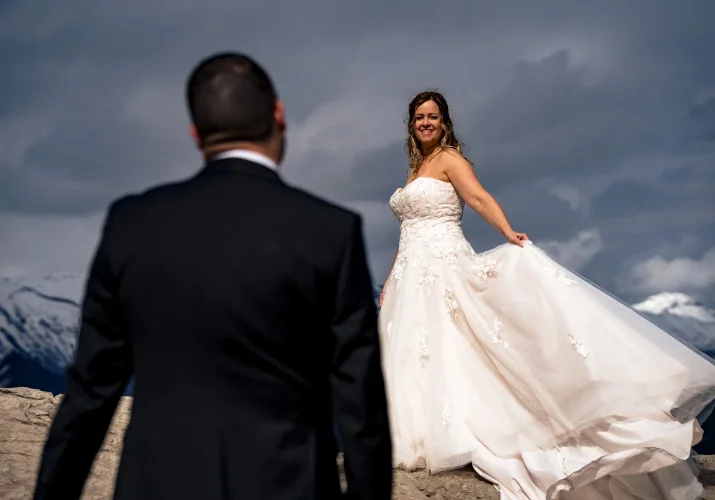 Bride holds her wedding dress and look at the groom.