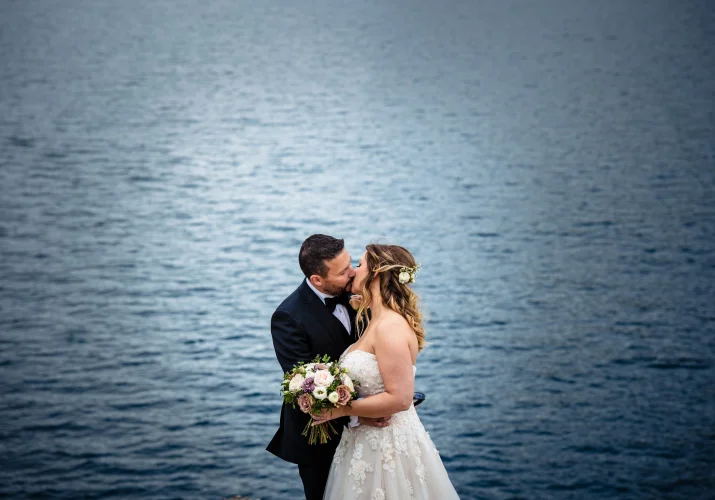 Bride and groom kiss at the lake in Banff.