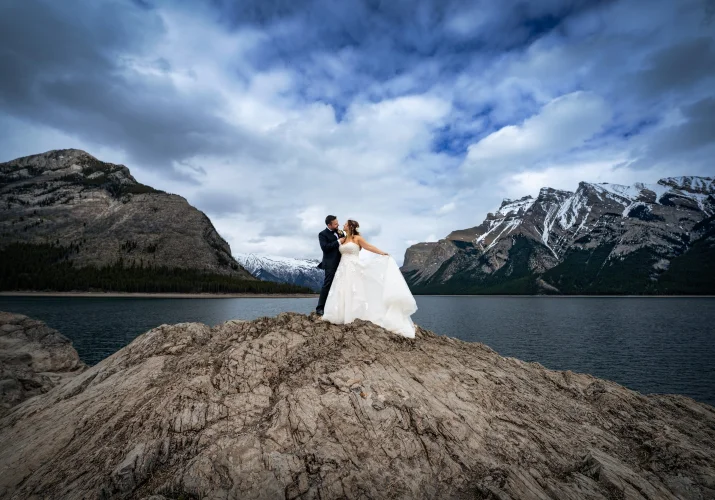 Newlyweds look at each other during wedding session with 4Eyes Photography at Minnewanka Lake