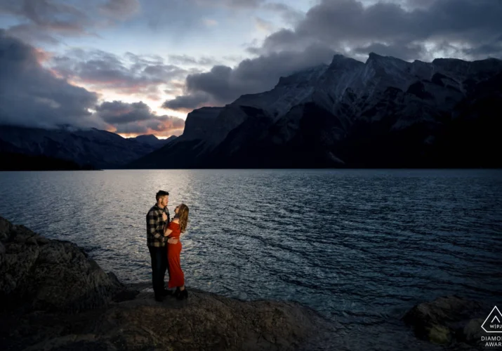 Pre wedding photo of engaged couple during sunrise at Minnewanka Lake in Banff.