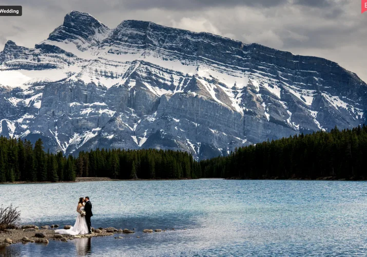 Wedding Award Photo of newlyweds standing by the edge of the lake in Banff. They ate surrounded by amazing Canadian Rockies.