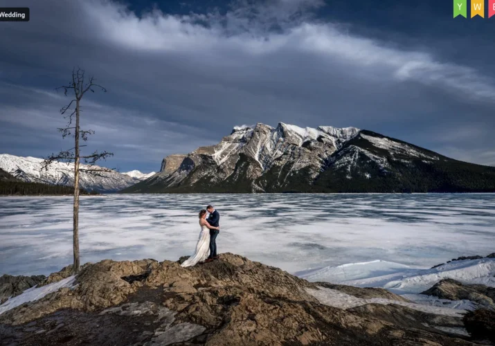 After-wedding photo of newlyweds in Banff. They hug at the frozen Minnewanka Lake.