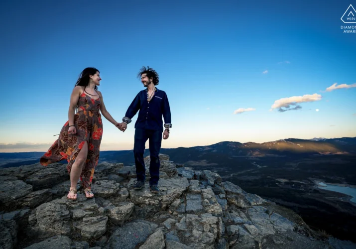 Engaged couple holds hands and look at each other during engagement session in Kananaskis Country Canada.