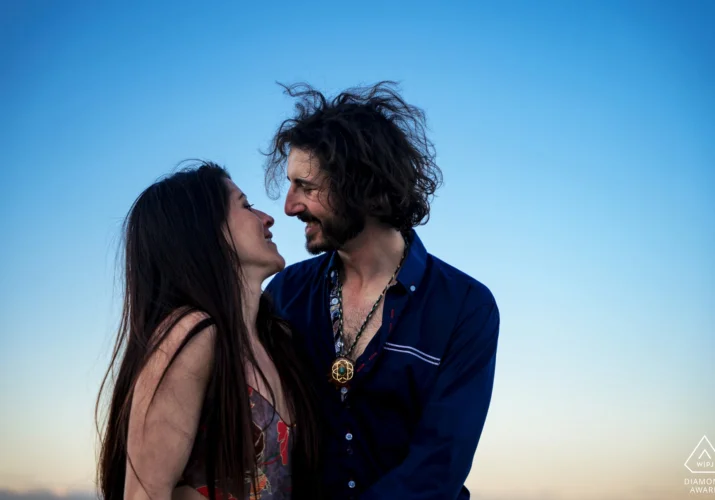 Engagement portrait of couple in love against a blue sky.