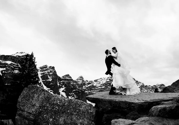 Groom lifts the bride and they both laugh during after wedding photo session at Moraine Lake