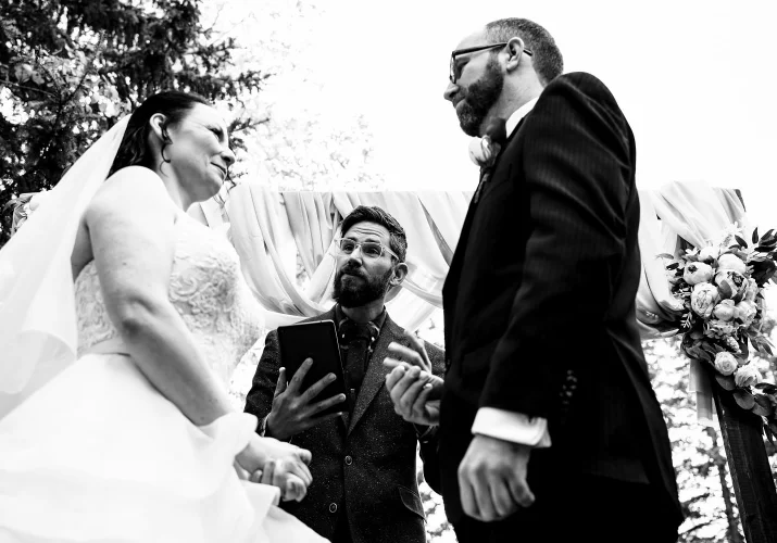 Officiant gives a speech to bride and groom during Banff Wedding. Black and White Photograph taken by the best Banff Wedding Photographer.