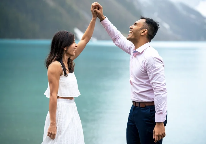Couple in love hold theirs hang above heads and laugh.