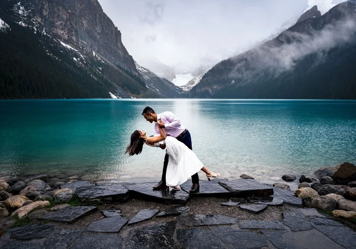 beautiful and young engaged couple dancing at the Lake Louise during their engagement session with best Calgary Wedding Photographer