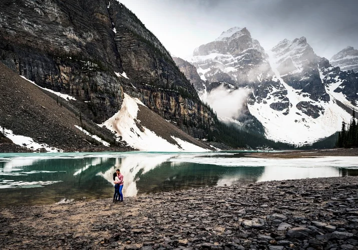 Amazing engagement portrait at Moraine Lake, on the background turquoise lake and snowy mountains.