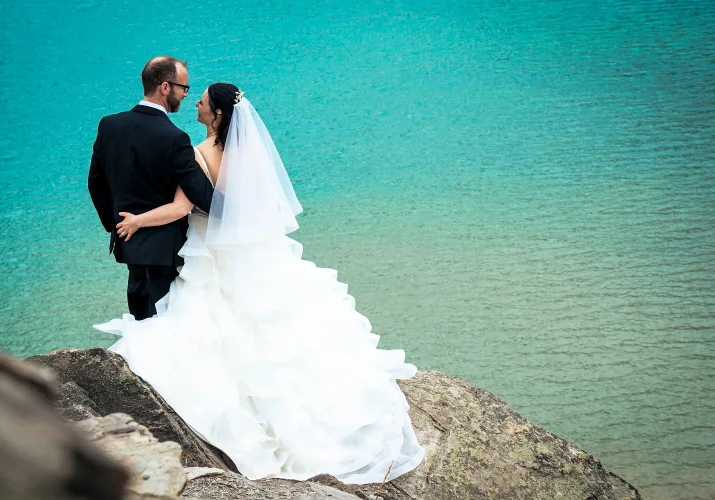 Bride grabs the grooms butt during wedding photo session by the lake