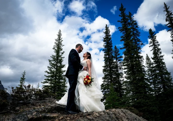 Bride and groom look at each other against a blue sky.