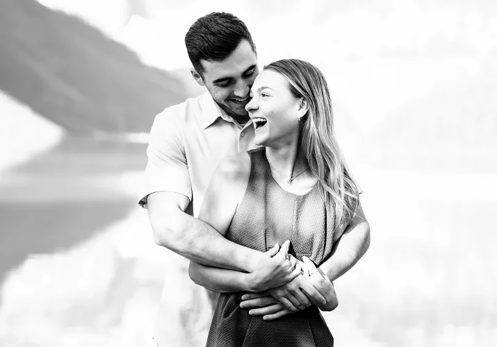 A man whispers his fiancee something to her ear . she loughs during this fun Banff Engagement Session with the best Wedding Photographer.