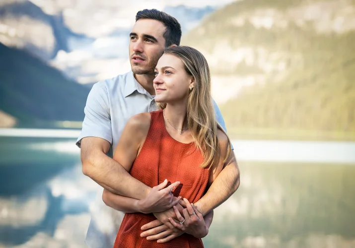 Romantic engagement portrait of couple looking at the same direction and hugging.