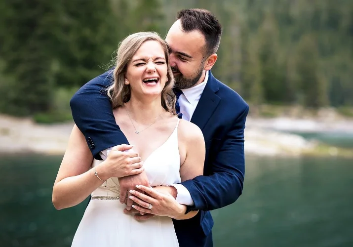 Groom stands behind bride and whisper something funny to her ear. They both lough,