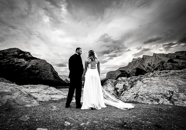 Bride and groom facing Minnewanka Lake and look at each other after Elopeoemt in Banff.