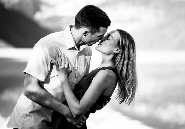 Intimate black and white engagement photography of couple kissing by the Lake Louise