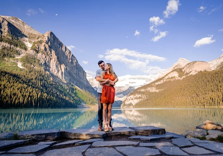 A men hugs his fiancee by the unique Lake Louise.