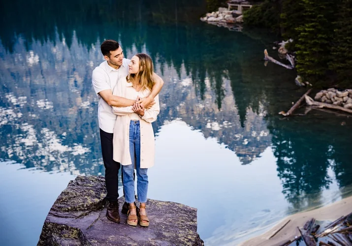Newly engaged couple poses in front of clear water of Moraine Lake for the best Banff Wedding Photographer 4Eyes Photography.