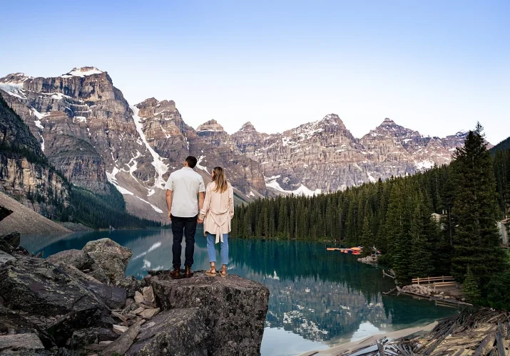Engaged couple adore the beauty of amazing Moraine Lake in valley of ten peeks