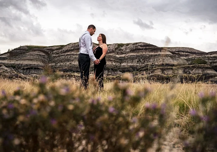 Men and woman holds their hands and look deeply into each others eyes during after wedding photo session at Horseshoe Canyon in Alberta, Canada.