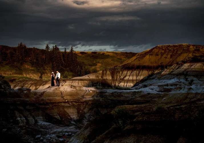 Stunning Photograph of couple holding hands highlighted by sun in Horseshoe Canyon in Alberta. Photo taken by Calgary Wedding Photographer Eliza Slobodzian.