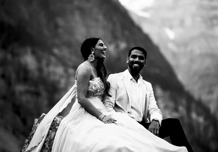 Black and white photography of Indian couple. they sit at the rock and laugh.