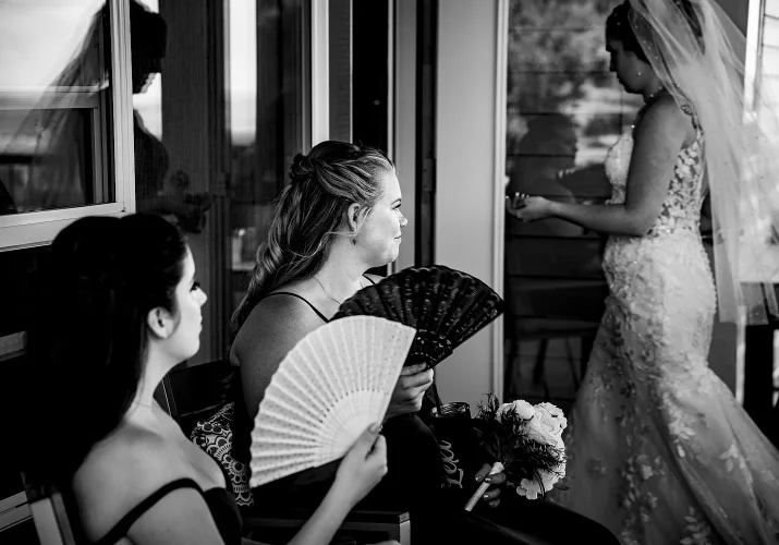 Bridesmaids cooling themselves down with the hand fans on the hot, summer Calgary Wedding.