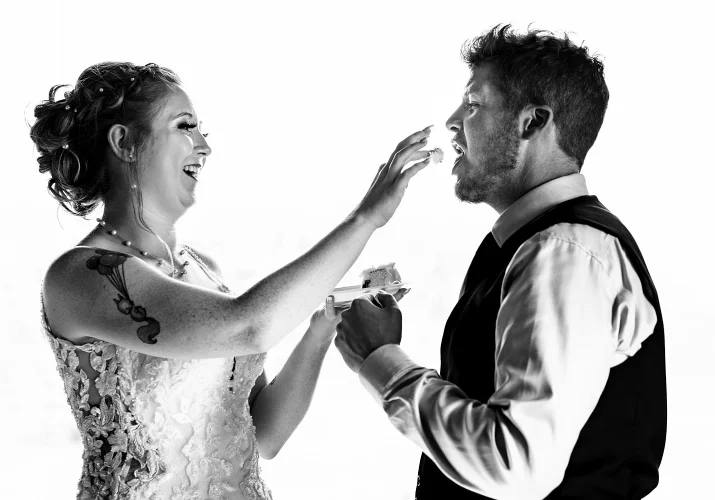Bride feeds a groom with a piece of wedding cake.