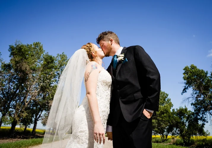 Bride and groom share a kiss during sunny wedding in Calgary
