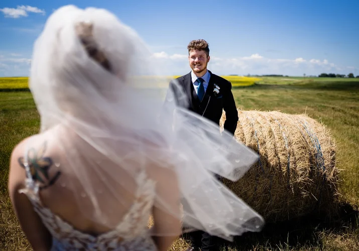 groom lean over on hay cone and look at the bride