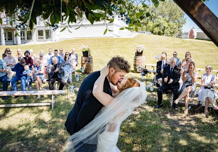 First kiss of the bride and groom. Guest are clapping theirs hands. Studding countryside wedding ceremony outside of Calgary.