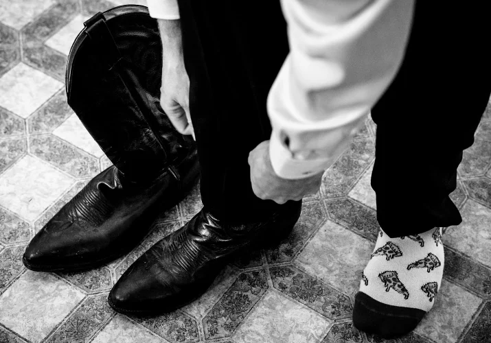 Groom puts a cowboy boots before the countryside wedding ceremony in Calgary.