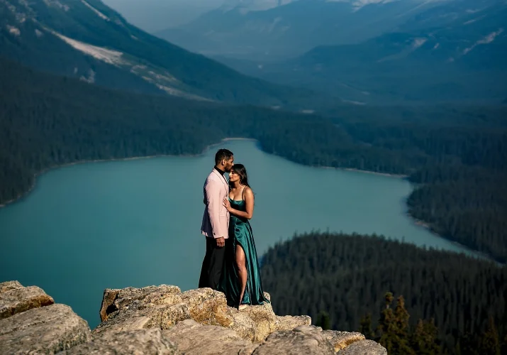 Amazing portrait of engaged couple standing at the top of the mountain. On the background blue Peyto Lake.
