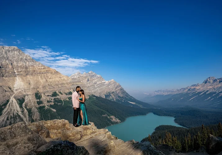 Engaged Photo session at Peyto Lake of couple in love standing at the edge of the mountain in a hug.