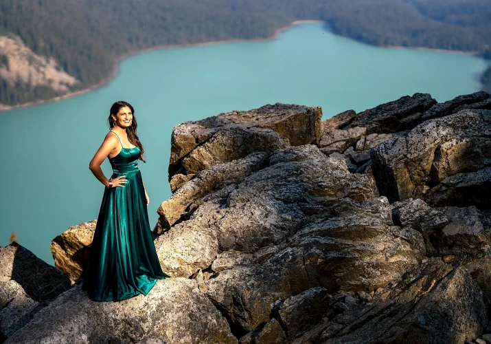 beautiful Indian lady in a long, green dress stands by the peyto Lake in Canada.
