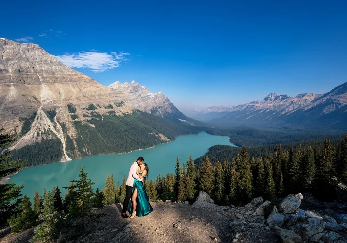 Lady in a long, green dress dances with her fiancee at the studding location Peyto Lake in Canada.
