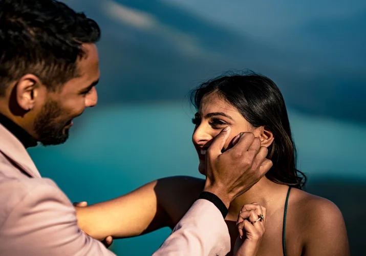 Man wipes the tears of happiness from his fiancee's cheek.