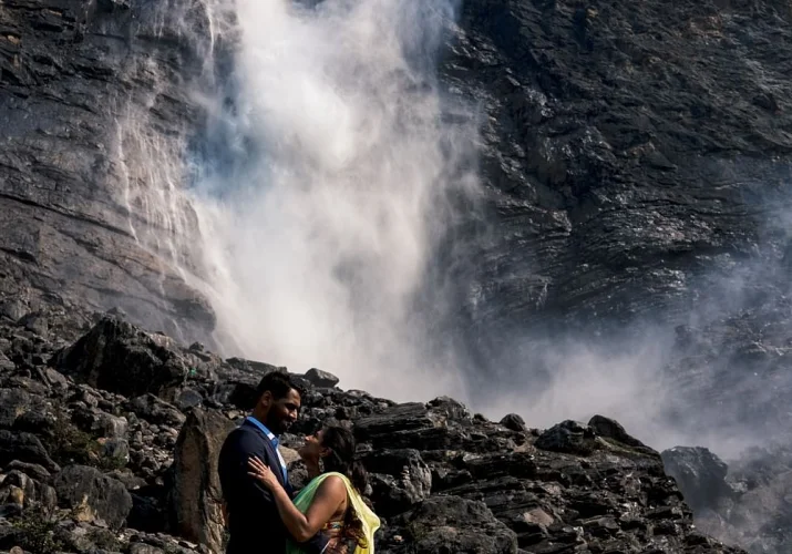 Indian Couple wearing traditional outfits on their engagement session at Takakkaw Falls. They look deeply into each others eyes.