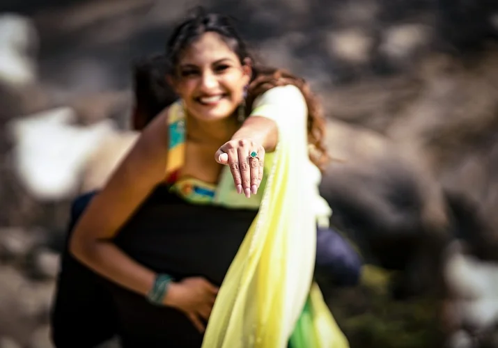 Beautiful Indian girl shows her engagement ring while her fiancee carry her on his shoulder.