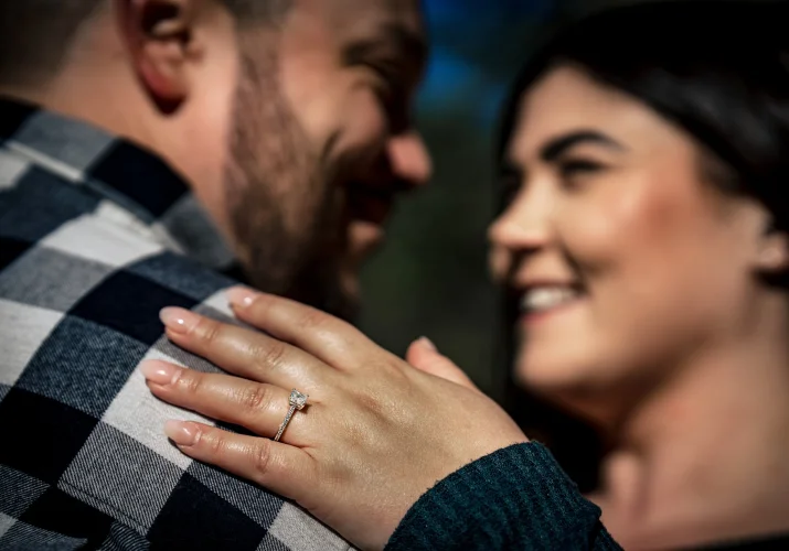 Engaged people look at each other . Girls hand on the man's shoulder with beautiful engagement ring.