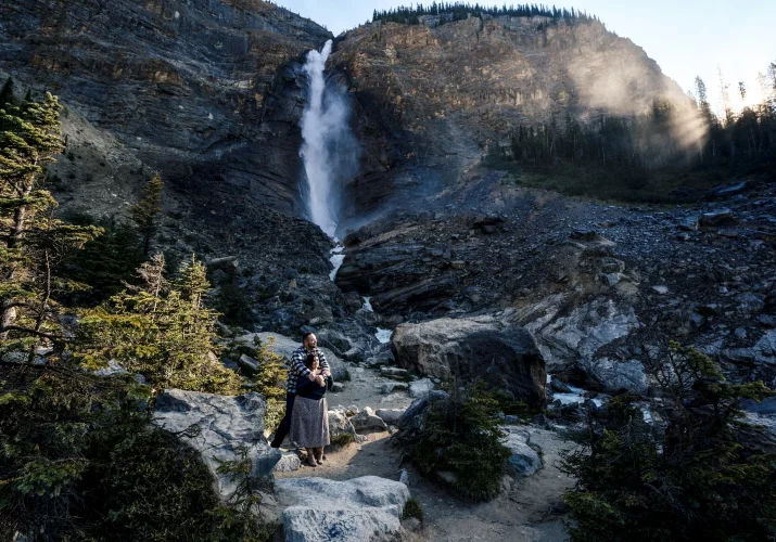 Man hugs his fiancee at amazing waterfall in Banff.
