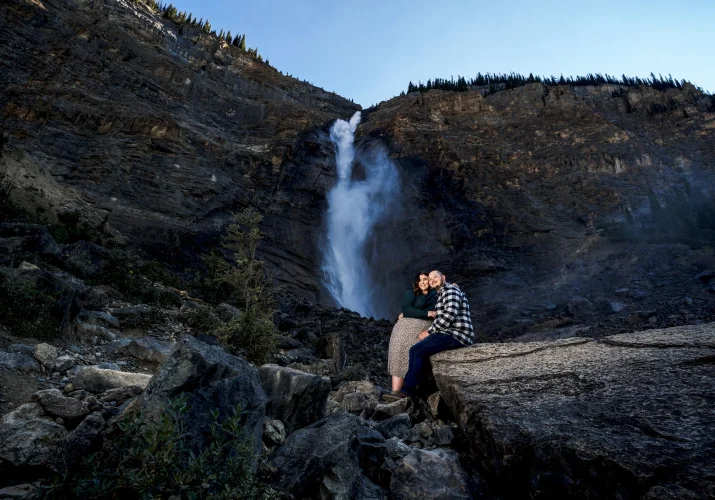 Couple in love sit at the rock at Takakkaw Falls.