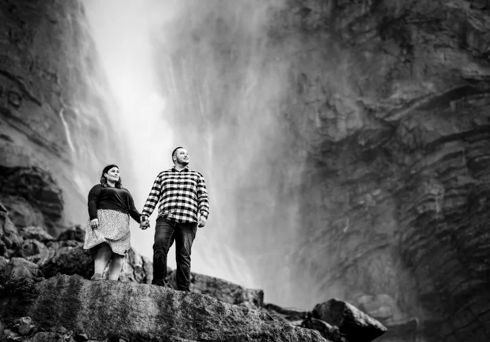 Man and lady hold their hands at the waterfall in Banff.