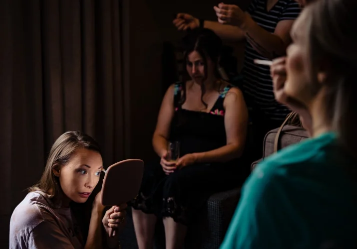 Bridesmaids fix their make up in the hotel room.