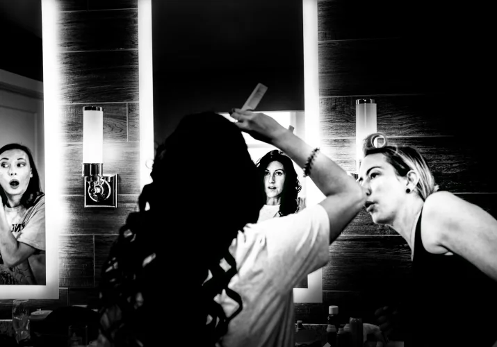 Bride fixing hair hair in the mirror while her friend look at her.