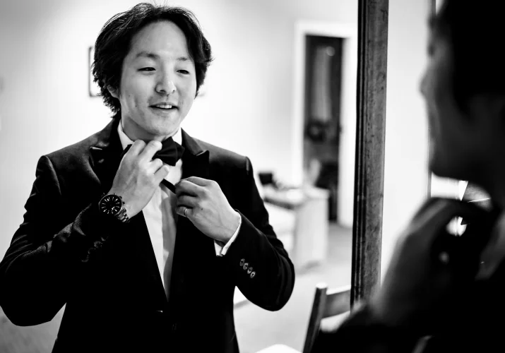 The groom fix his bow tie in front of the mirror before wedding at Emerald Lake.