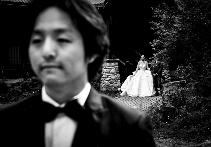 Groom waits for the bride while she walks behind him.