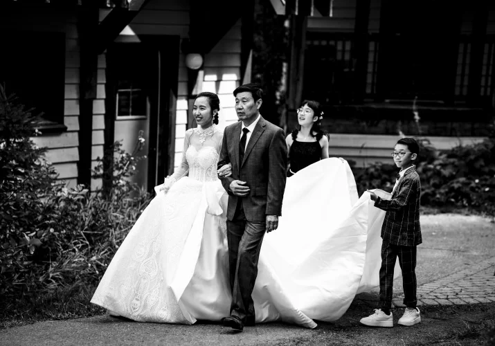 bride and her father heading for the wedding ceremony at Emerald Lake. Kids help with her giant wedding dress.