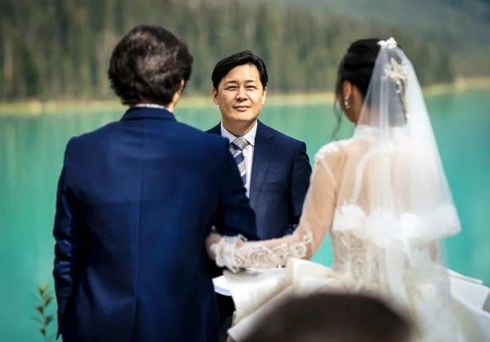 Bride and groom standing in front of officiant At Emerald Lake, Canada
