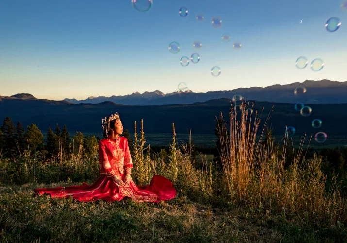 Bride sits on the grass in her stunning , traditional, Asian wedding dress in Bandd.